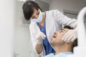 the female dentist is extracting the tooth of the patient in the clinic