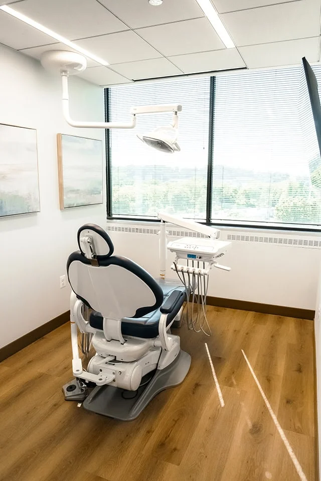 Dental treatment room with a modern dental chair, overhead light, and dental instruments, emphasizing patient comfort at West Periodontics and Dental Implants in Timonium, MD.