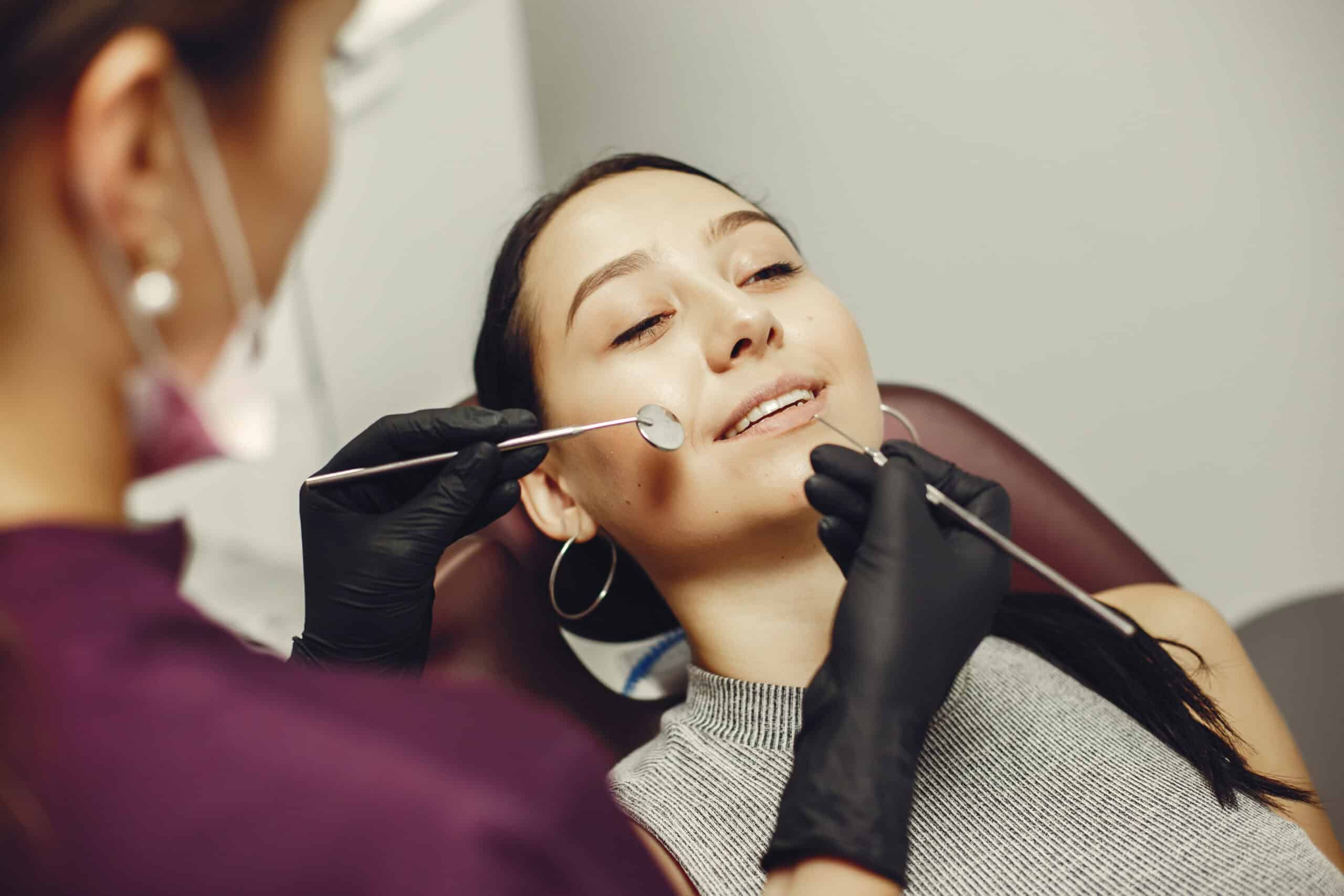 Dentist examining patient’s teeth with dental tools, highlighting modern dental care and gum recession treatments.