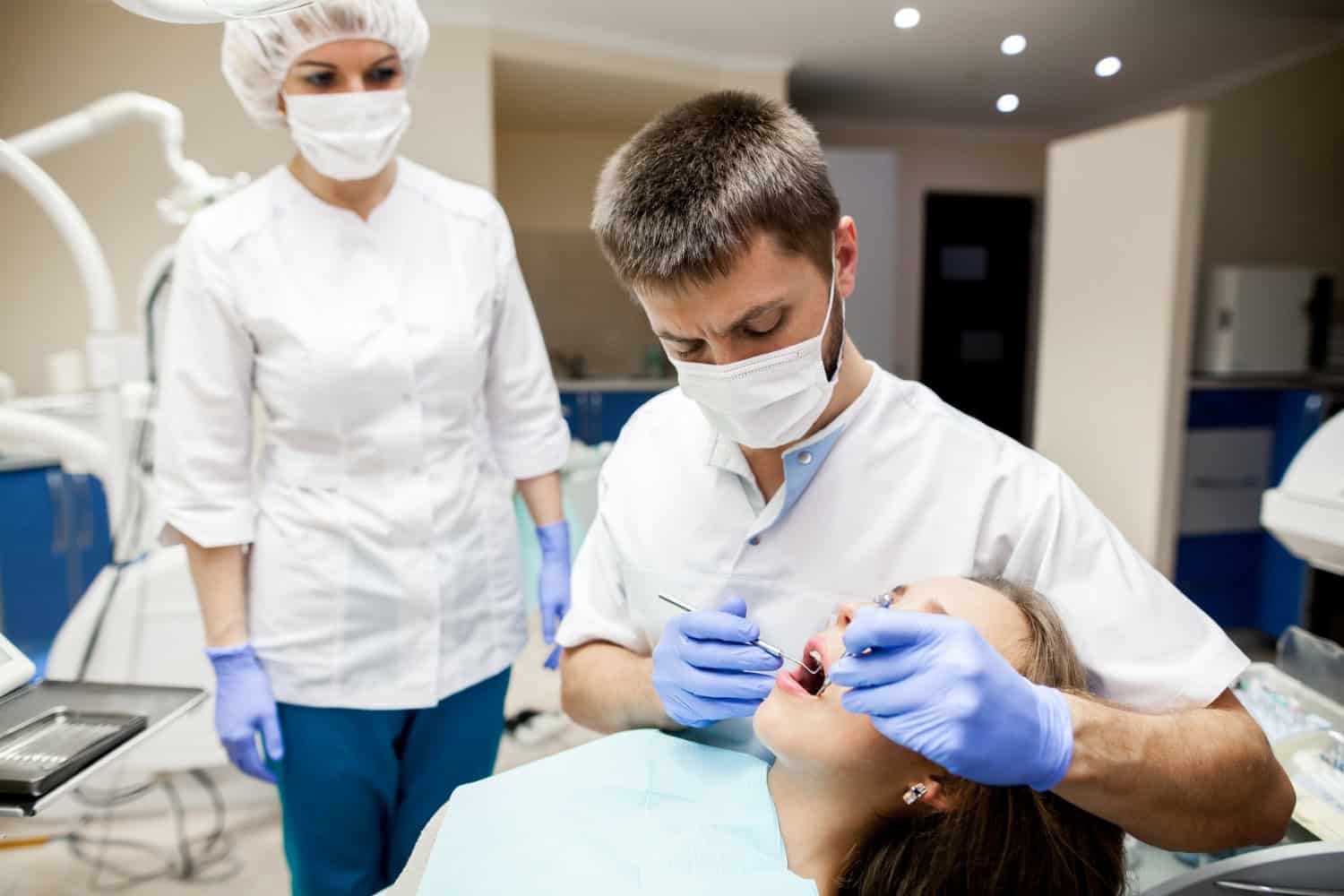 Dentist performing a bone grafting procedure on a patient during dental treatment with surgical staff in a clinical setting.