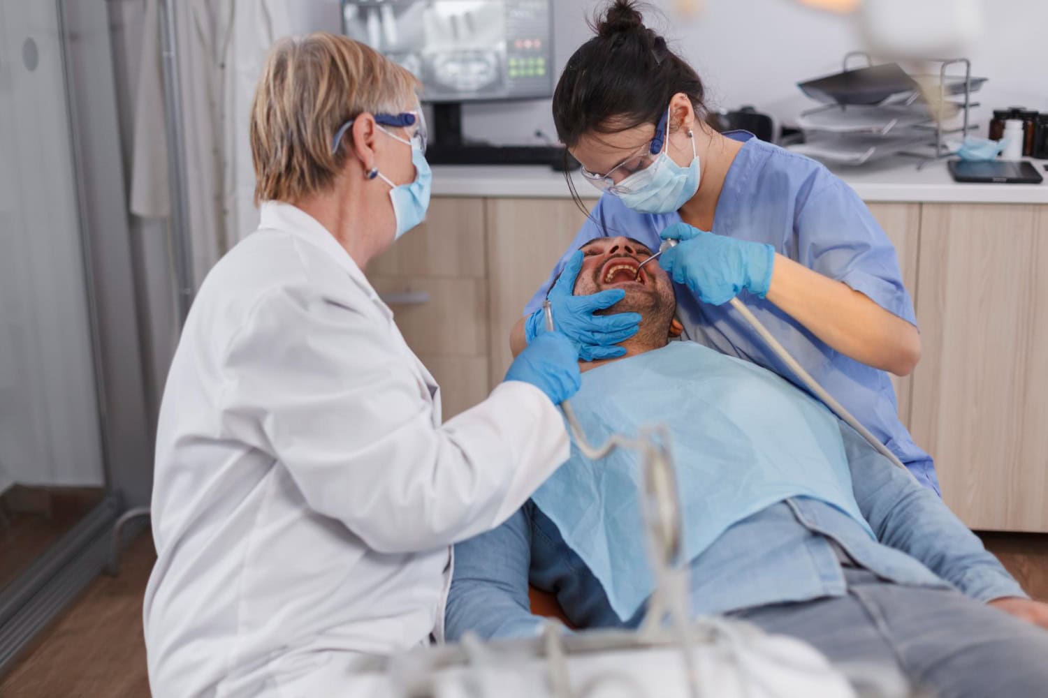 Dental professionals performing an oral surgery procedure on a patient in a dental clinic.