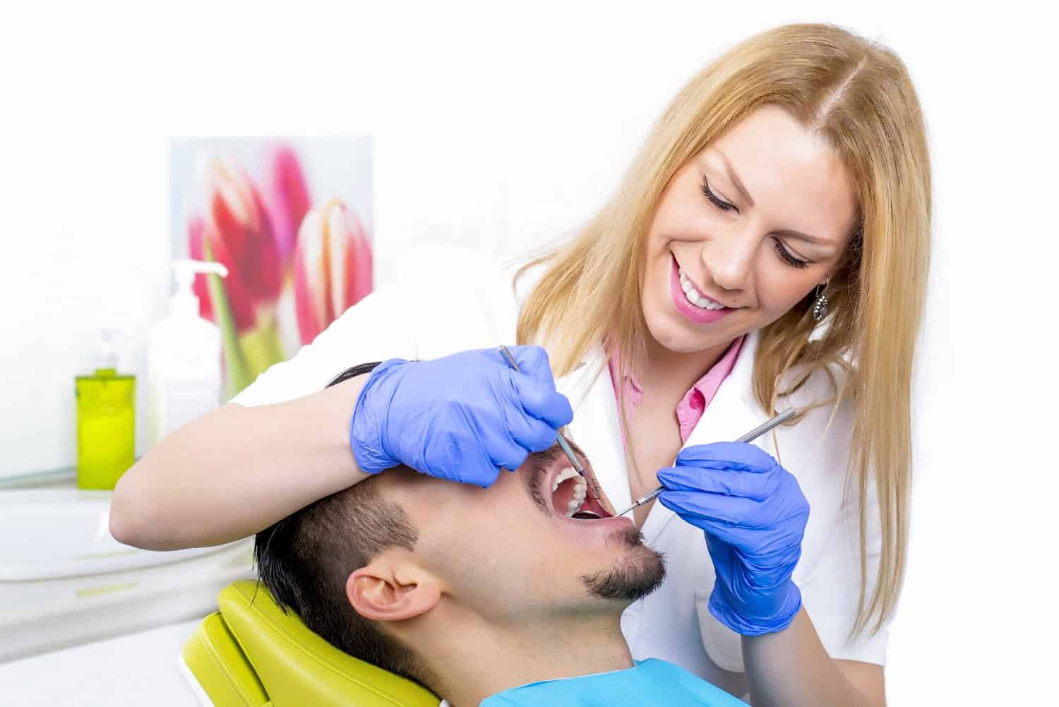 Periodontist examining gums to assess factors affecting laser gum surgery recovery time.